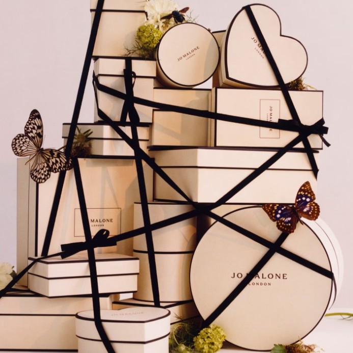 jo malone london advent calendar 2026 A stack of cream-coloured Jo Malone gift boxes tied with black ribbons, decorated with butterflies and small white flowers.