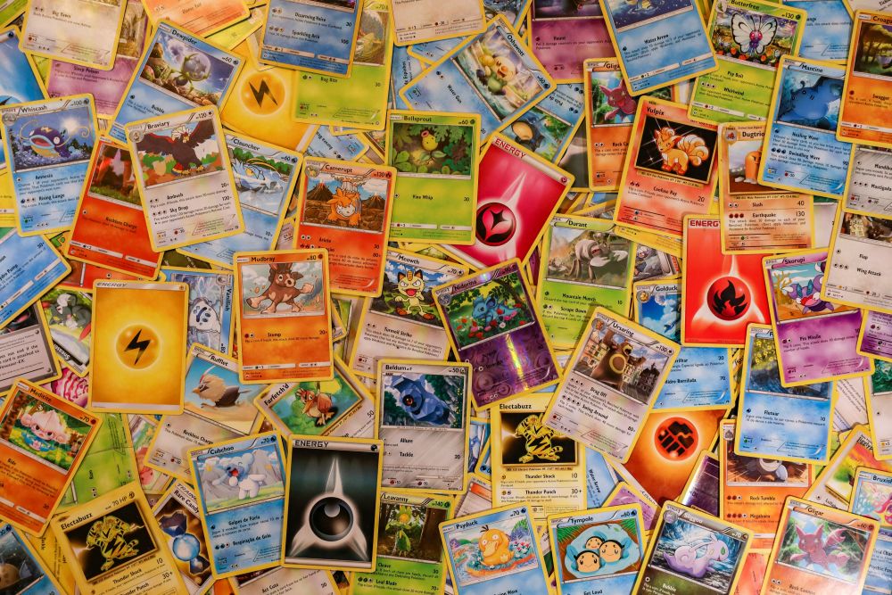 pokemon cards A scattered collection of various Pokémon trading cards, showing different characters, types, and energy cards on a flat surface.