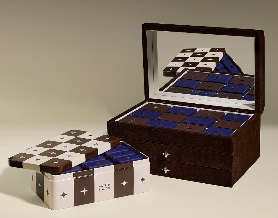 Two boxes of assorted chocolates, one open and mirrored, the other partially open, both featuring a brown, white, and blue geometric star pattern on the lid.