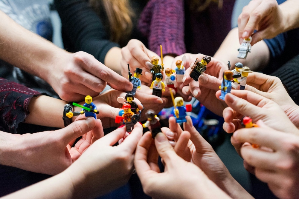 An image showing different LEGO minifigures being held in people's hands