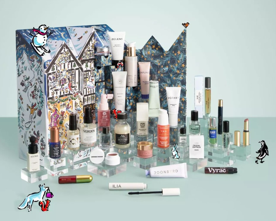 liberty beauty advent calendar 2026 A variety of skincare and make-up products are displayed in front of two decorative boxes with illustrated winter and animal designs.