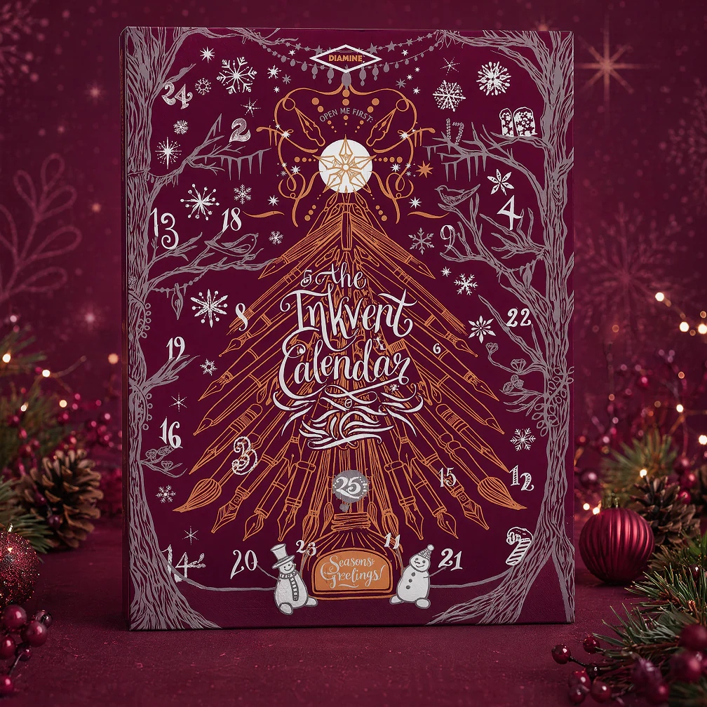 cult pens diamine advent calendar A maroon advent calendar with gold and white festive illustrations, labelled “The Inkvent Calendar,” stands on a table with holiday decorations and ornaments in the background.
