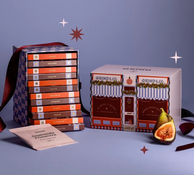 grind coffee bean advent calendar 2026 Stacked advent calendar boxes, a larger gift box with café illustration, a sliced fig, and a cloth pouch are arranged on a purple background with star graphics and red ribbon accents.
