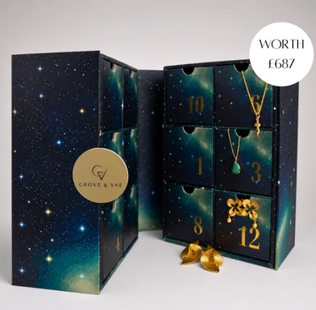 grove and vae 2026 calendar A dark star-themed jewellery advent calendar box with numbered drawers, containing gold jewellery pieces, and a label stating “WORTH £687.”.