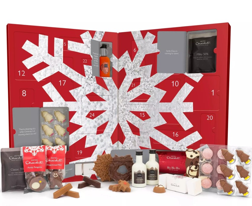 hotel chocolat 2026 Red Advent calendar box with numbered doors, silver snowflake design, and various chocolates, snacks, and small toiletries displayed in front.