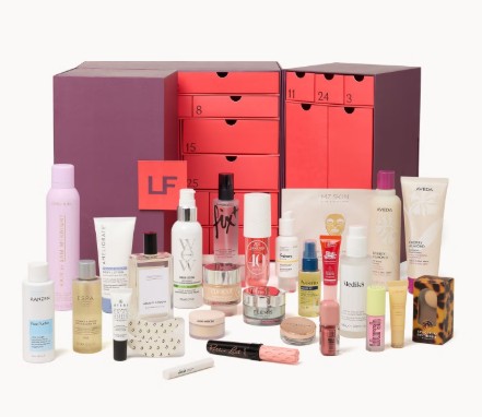 lookfantastic beauty advent calendar 2026.png A collection of assorted skincare, haircare, and beauty products displayed in front of a purple and red advent calendar box with numbered drawers.