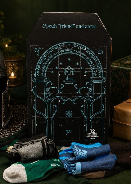 lotr A Lord of the Rings-themed sock advent calendar with Elvish script design, surrounded by gift boxes, a helmet, and three pairs of socks in front: green, black, and blue.