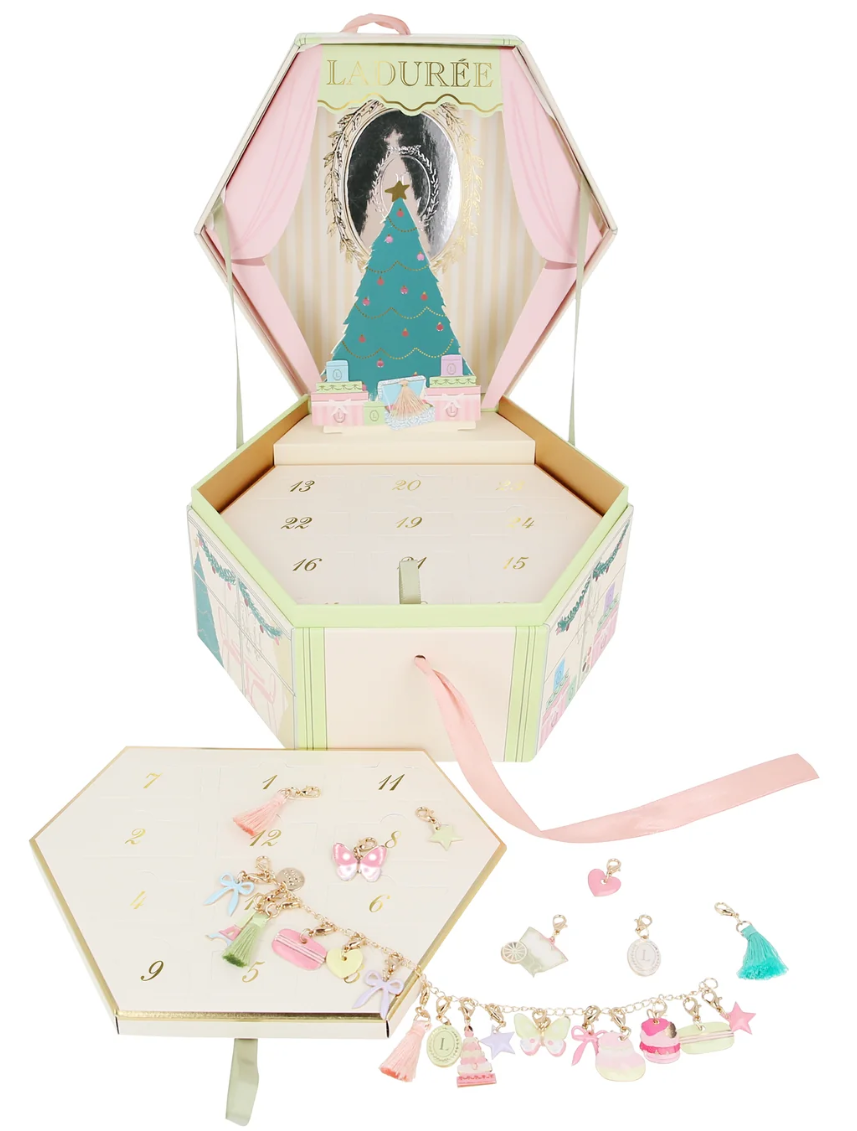 Laduree advent calendar box with numbered compartments, a Christmas tree illustration, and various pastel charms and trinkets displayed in front.