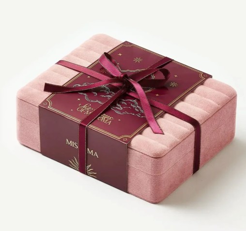 Rectangular pink velvet jewellery box with a burgundy ribbon and card, featuring gold detailing and “MISOMA” branding on the front.