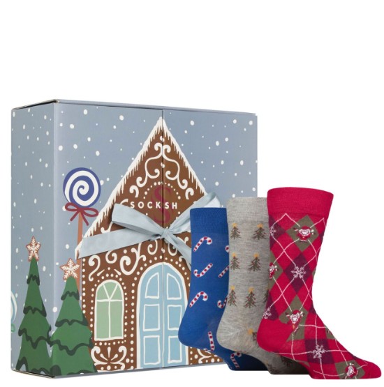 sockshop mens 2026 Three pairs of holiday-themed socks in front of a gingerbread house gift box decorated with trees and snow.