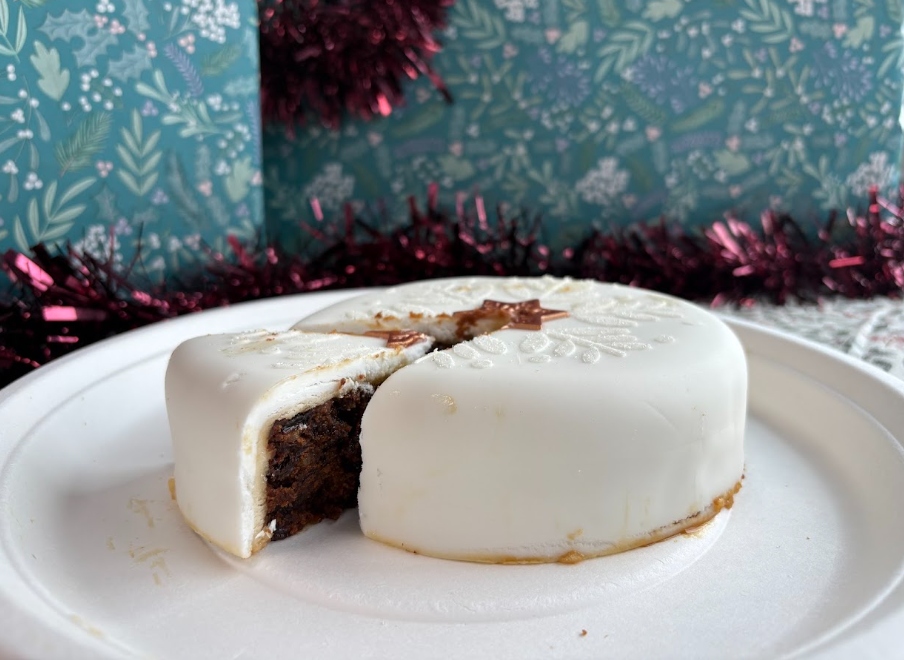 aldi christmas cake 2026 An image showing Aldi's 2026 Christmas cake with a slice taken out of it for serving
