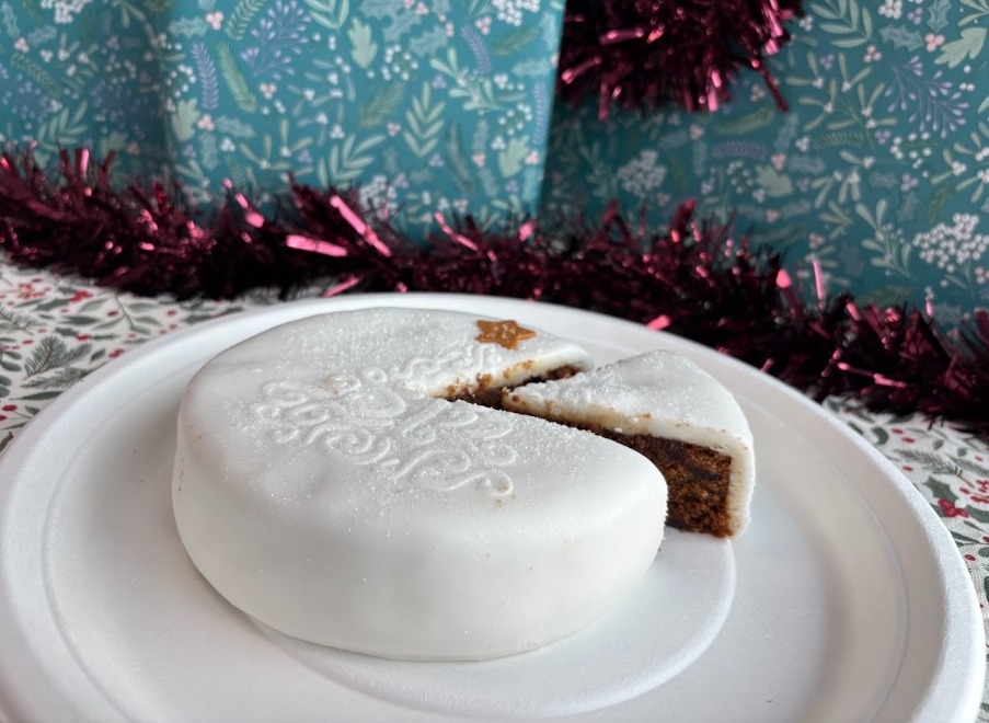 morrisons christmas cake 2026 An image showing a white Morrison's iced fruit cake with a piece taken out of it
