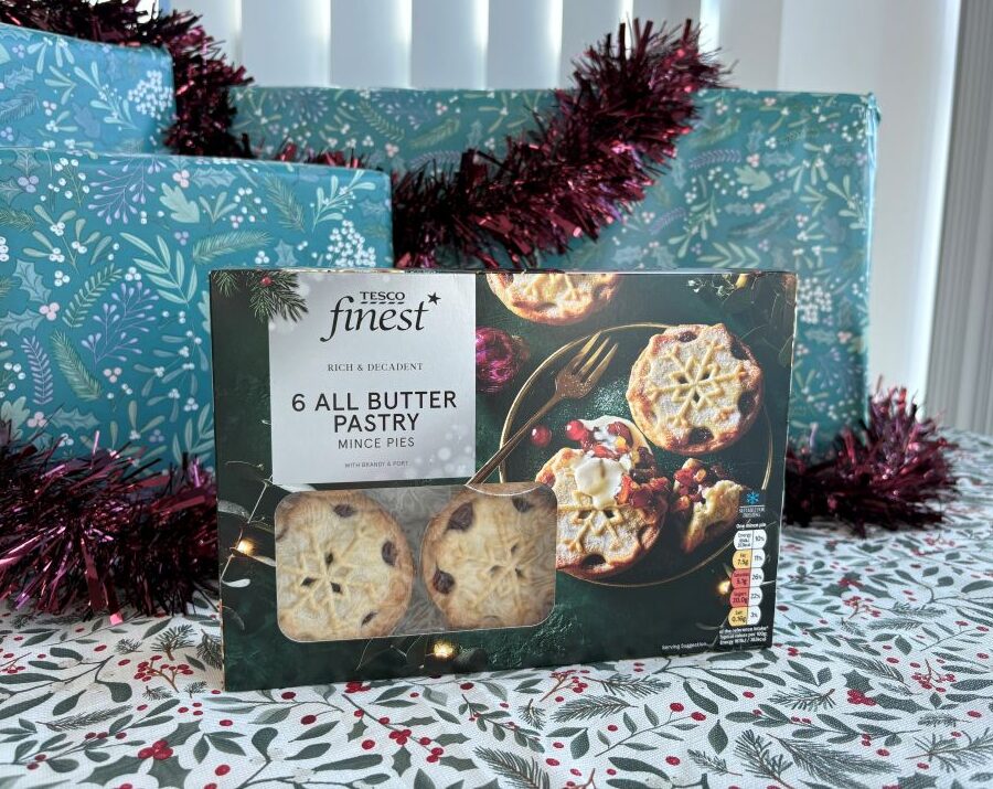 Box of Tesco Finest mince pies in front of Christmas-themed gift wrapping paper.